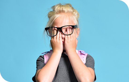 Young girl wearing glasses and rubbing her eyes